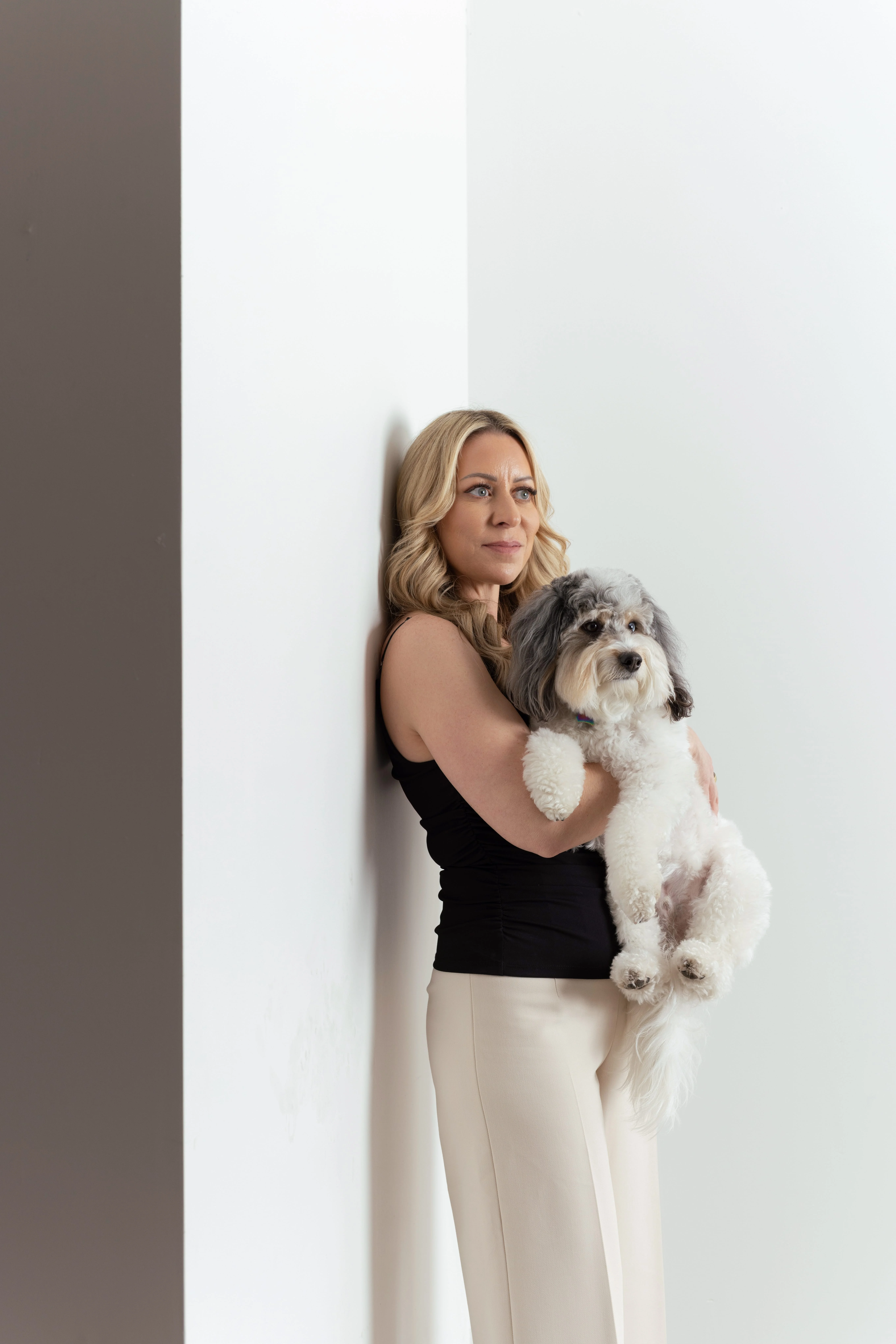 Woman in black top holding a fluffy white and gray dog